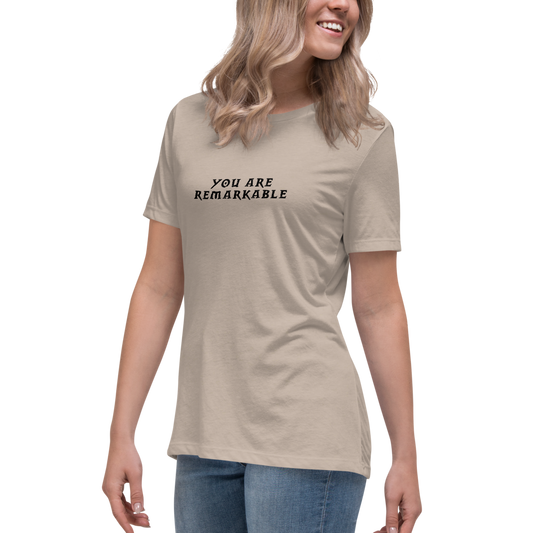 "You are remarkable" printed on a heather stone women's relaxed t-shirt worn by a female