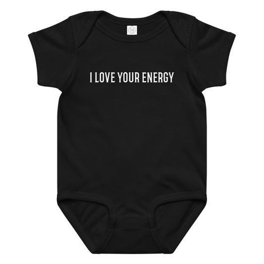 "I love your energy" printed on a black baby jersey bodysuit laying on a flat surface amongst other clothes