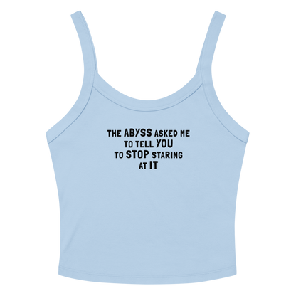 "The Abyss asked me to tell you to stop staring at it" printed on a solid baby blue blend women's micro-rib tanktop laying on a flat surface amongst sunglasses and shorts