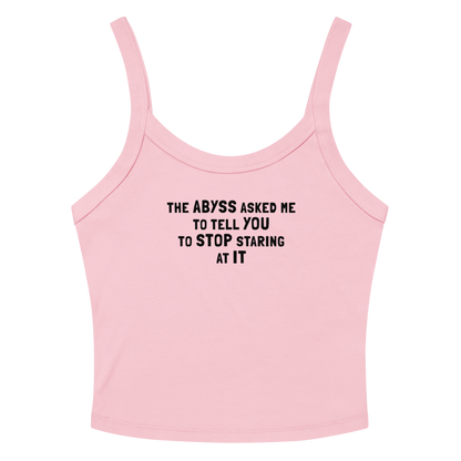 "The Abyss asked me to tell you to stop staring at it" printed on a solid pink blend women's micro-rib tanktop laying on a flat surface amongst sunglasses and shorts