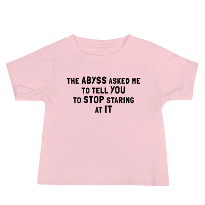 "The Abyss asked me to tell you to stop staring at it" printed on a pink baby jersey short sleeve tee laying on a flat surface