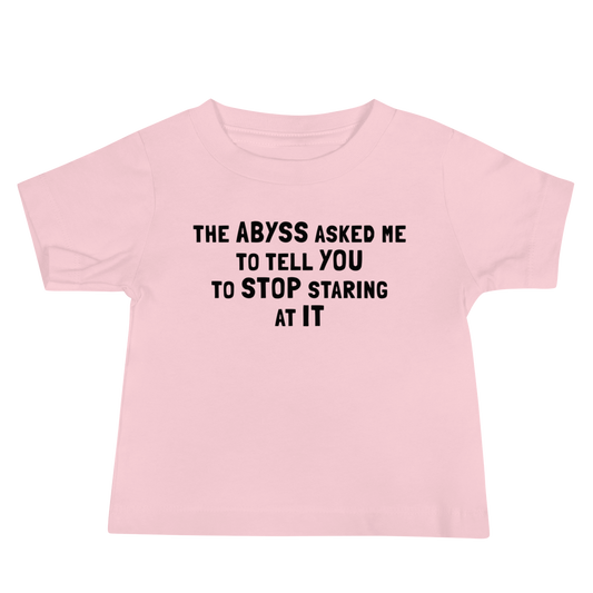 "The Abyss asked me to tell you to stop staring at it" printed on a pink baby jersey short sleeve tee laying on a flat surface