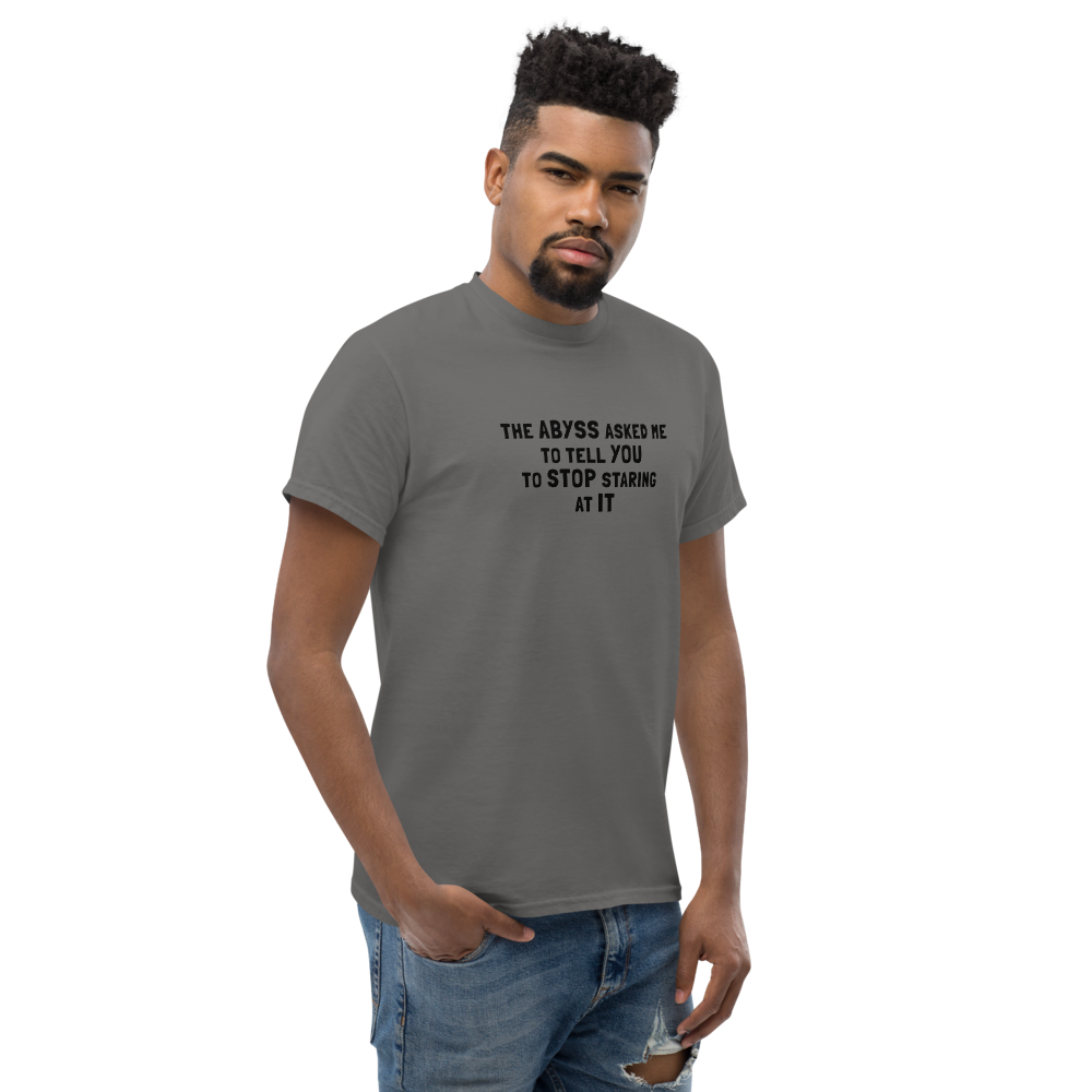 "The Abyss asked me to tell you to stop staring at it" printed on a charcoal unisex classic tee worn by a male