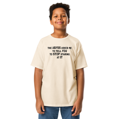 "The Abyss asked me to tell you to stop staring at it" printed on a natural youth classic tee worn by a male