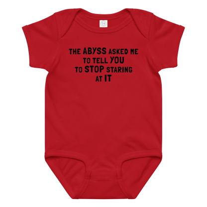 "The Abyss asked me to tell you to stop staring at it" printed on a red baby jersey bodysuit laying on a flat surface amongst other clothes