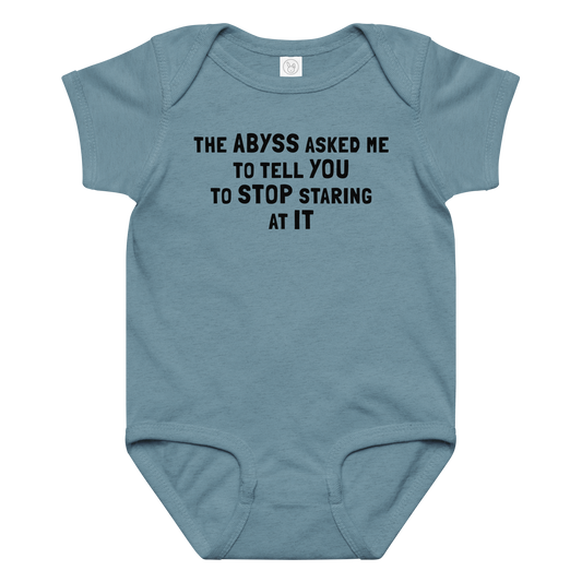 "The Abyss asked me to tell you to stop staring at it" printed on a vintage indigo baby jersey bodysuit laying on a flat surface amongst other clothes
