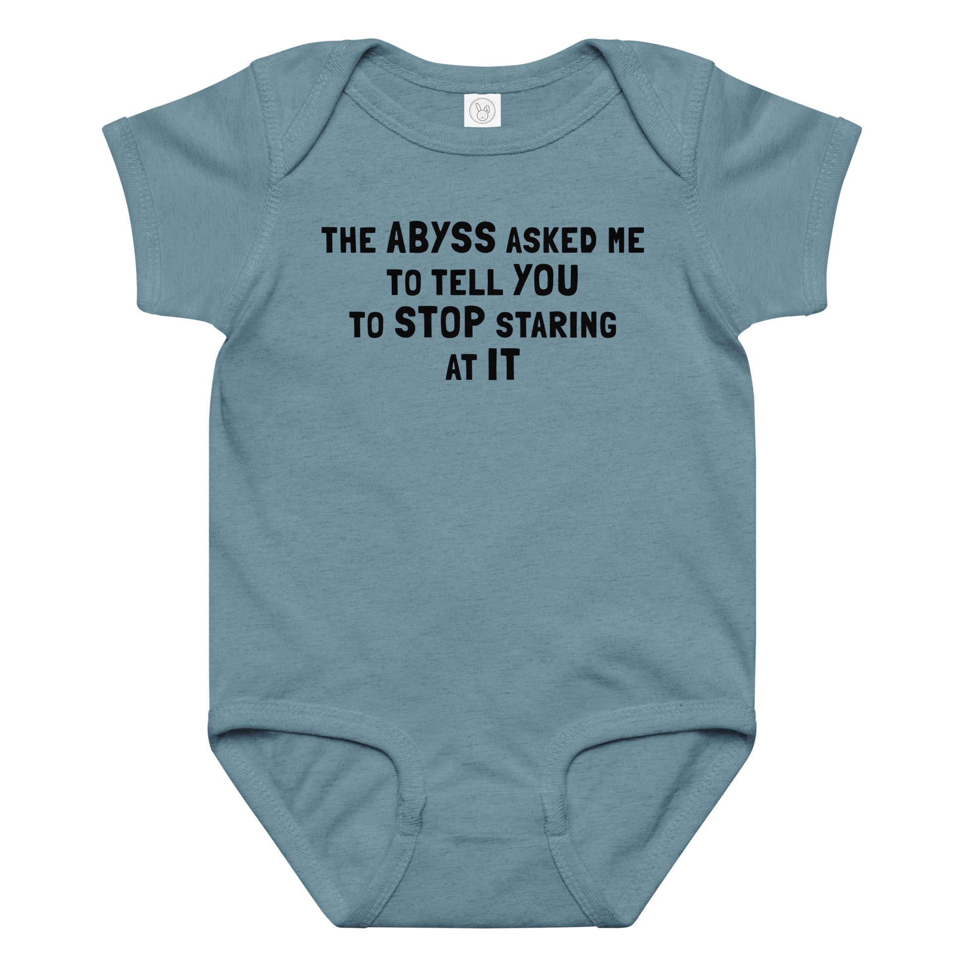 "The Abyss asked me to tell you to stop staring at it" printed on a vintage indigo baby jersey bodysuit laying on a flat surface amongst other clothes