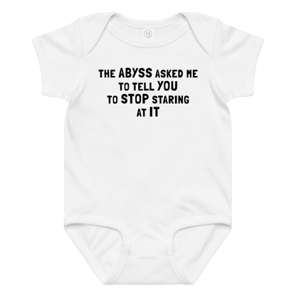 "The Abyss asked me to tell you to stop staring at it" printed on a white baby jersey bodysuit laying on a flat surface amongst other clothes