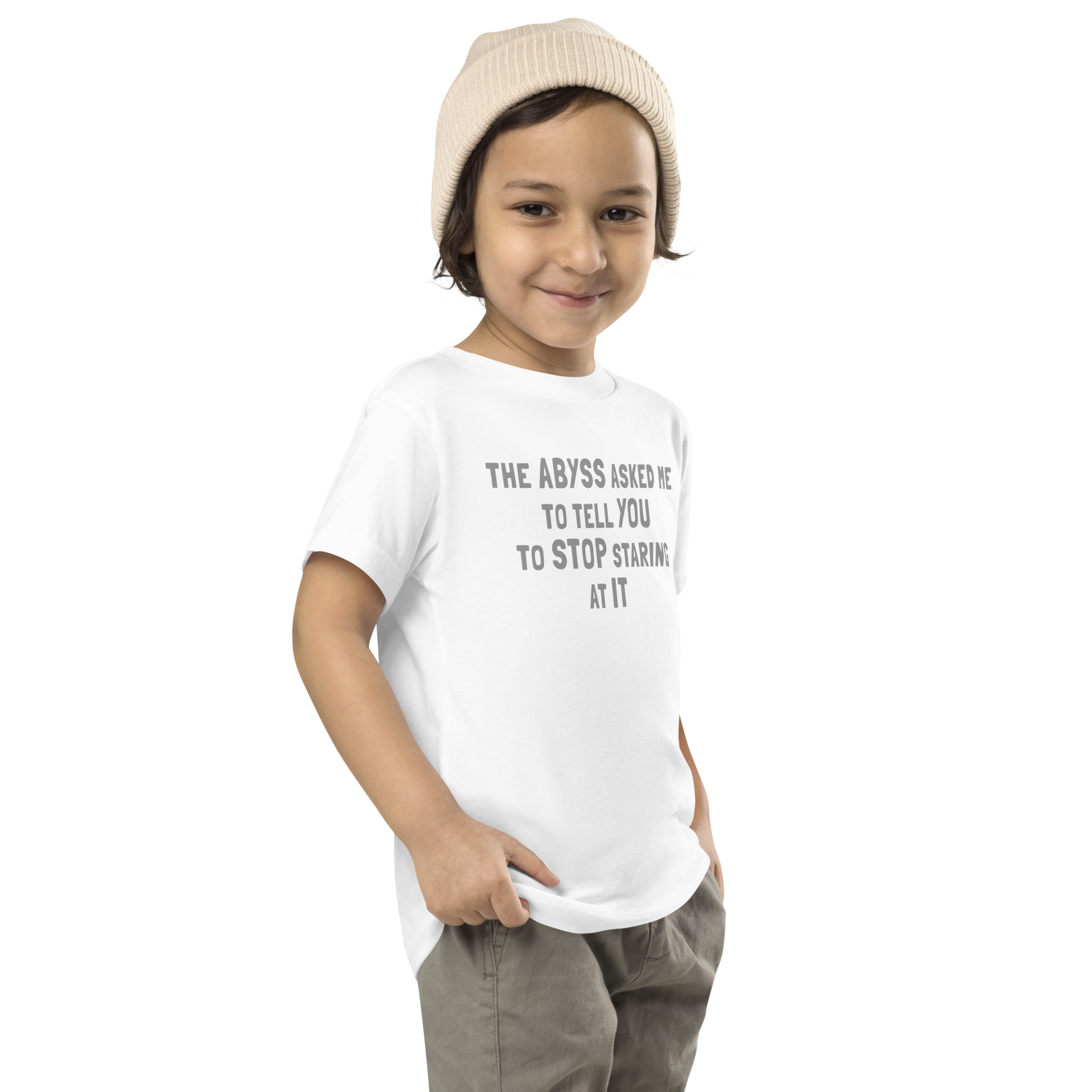 "The Abyss asked me to tell you to stop staring at it" printed on a white toddler short sleeve tee worn by a male who is also wearing a knit cap