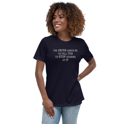 "The Abyss asked me to tell you to stop staring at it" printed on a navy women's relaxed t-shirt worn by a female