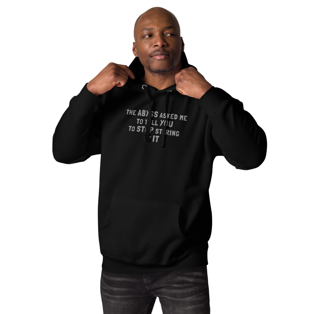 "The Abyss asked me to tell you to stop staring at it" printed on a black unisex hoodie worn by a male