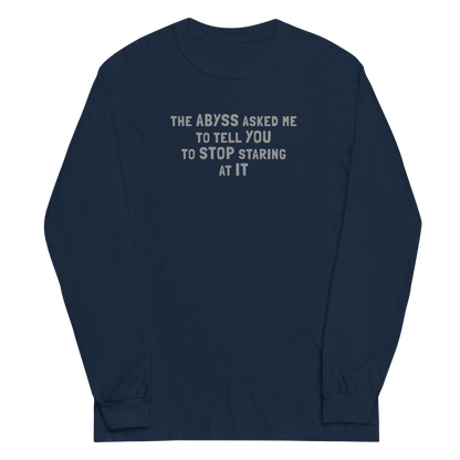 "The Abyss asked me to tell you to stop staring at it" printed on a navy men's long sleeve shirt laying on a flat surface