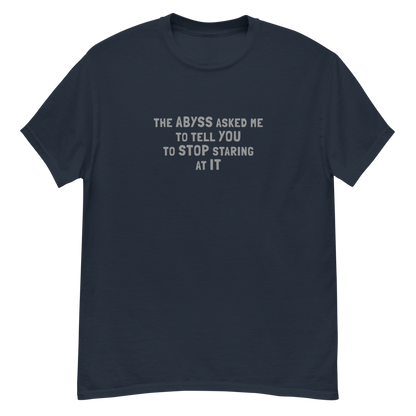 "The Abyss asked me to tell you to stop staring at it" printed on a navy unisex classic tee laying on a flat surface