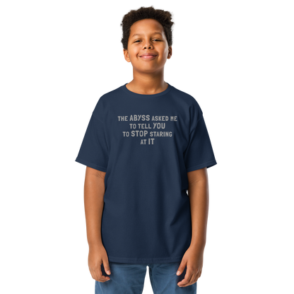 "The Abyss asked me to tell you to stop staring at it" printed on a navy youth classic tee worn by a male