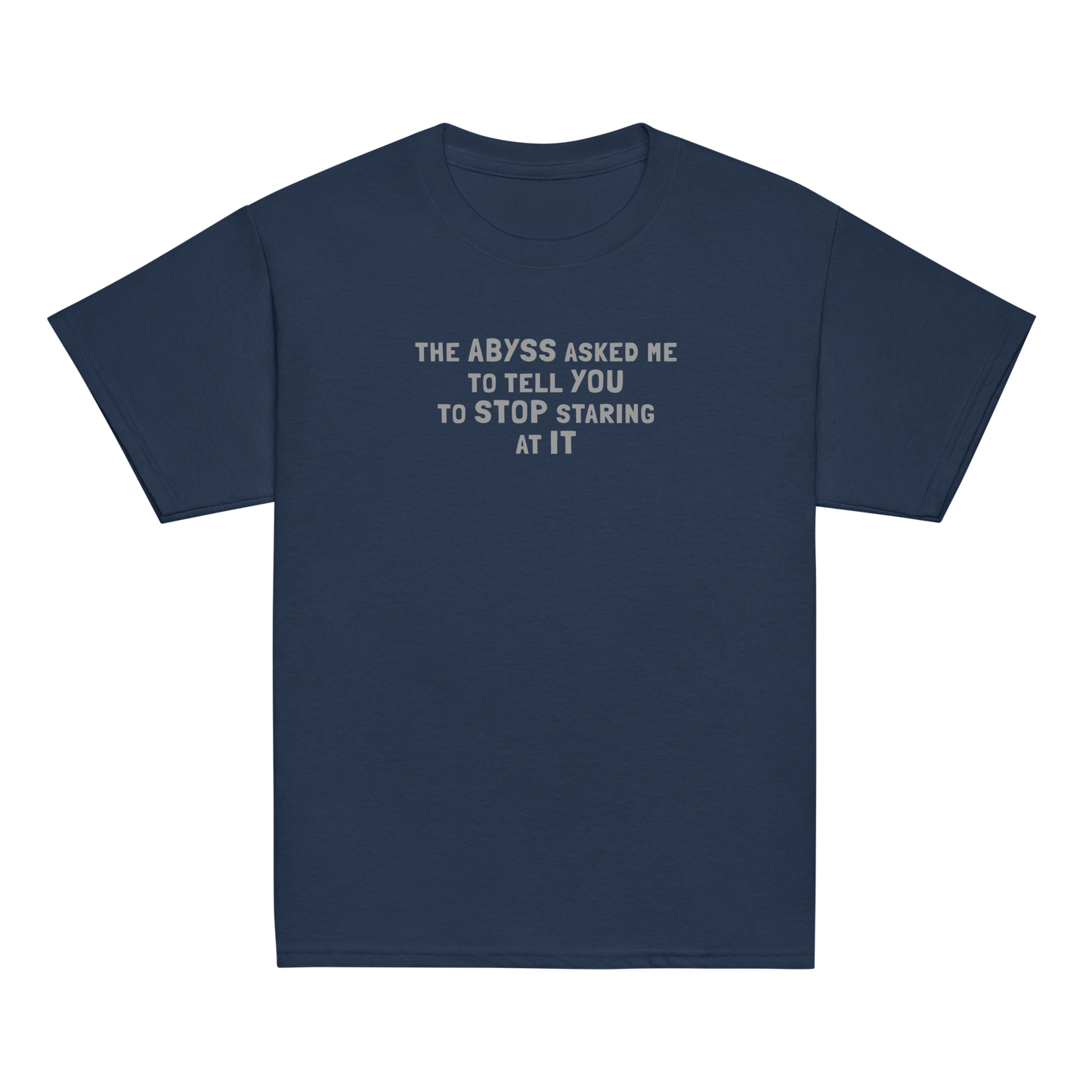 "The Abyss asked me to tell you to stop staring at it" printed on a navy youth classic tee laying on a flat surface