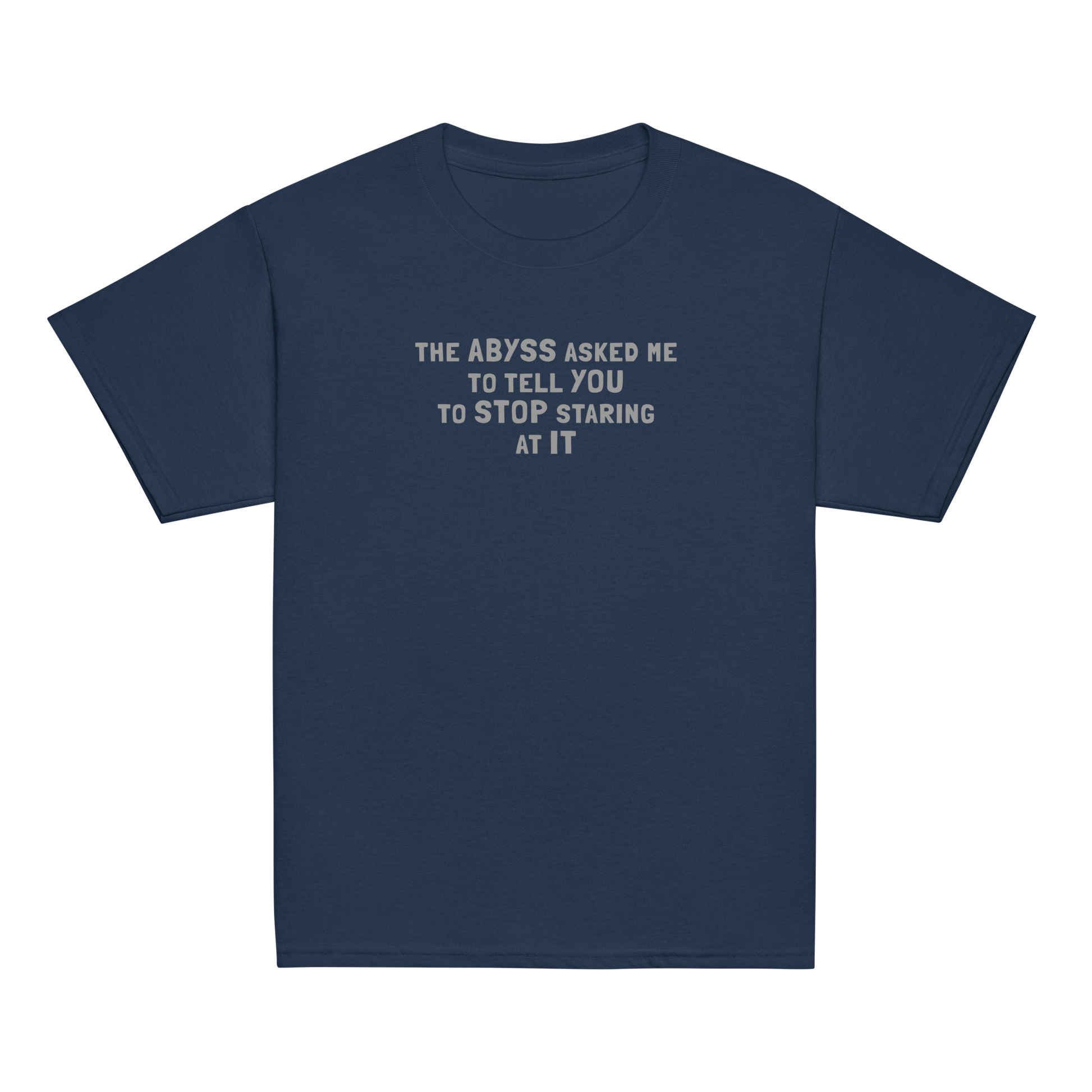 "The Abyss asked me to tell you to stop staring at it" printed on a navy youth classic tee laying on a flat surface