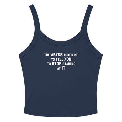 "The Abyss asked me to tell you to stop staring at it" printed on a solid navy blend women's micro-rib tanktop laying on a flat surface amongst sunglasses and shorts