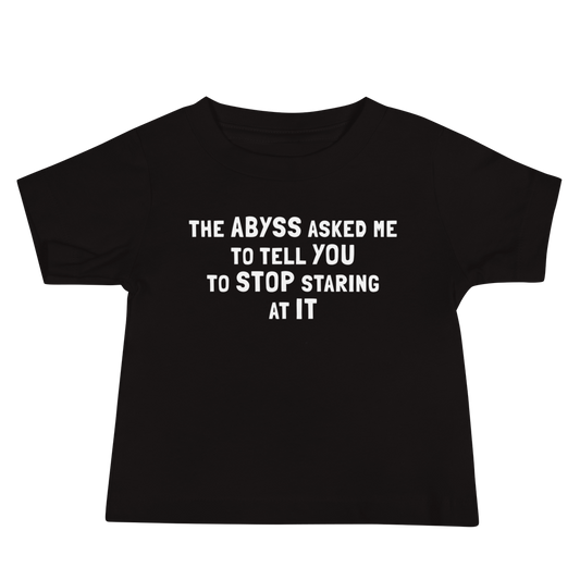"The Abyss asked me to tell you to stop staring at it" printed on a black baby jersey short sleeve tee laying on a flat surface