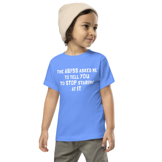"The Abyss asked me to tell you to stop staring at it" printed on a heather columbia blue toddler short sleeve tee worn by a male wearing a cap