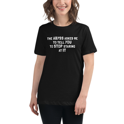 "The Abyss asked me to tell you to stop staring at it" printed on a black women's relaxed t-shirt worn by a female