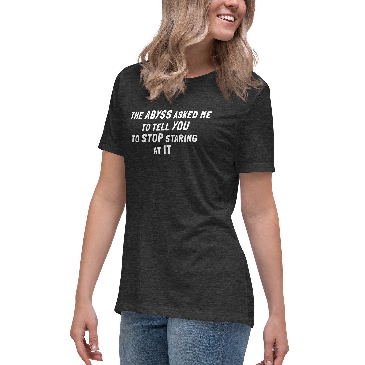 "The Abyss asked me to tell you to stop staring at it" printed on a dark grey heather women's relaxed t-shirt worn by a female