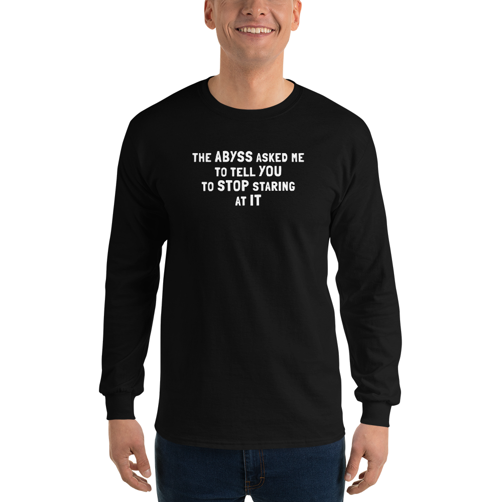"The Abyss asked me to tell you to stop staring at it" printed on a black men's long sleeve shirt worn by a male