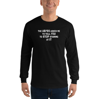 "The Abyss asked me to tell you to stop staring at it" printed on a black men's long sleeve shirt worn by a male
