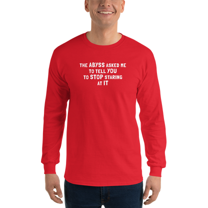 "The Abyss asked me to tell you to stop staring at it" printed on a red men's long sleeve shirt worn by a male