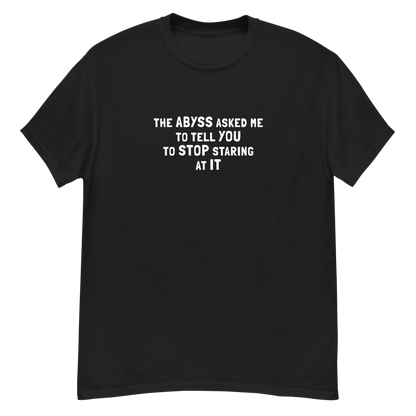 "The Abyss asked me to tell you to stop staring at it" printed on a black unisex classic tee laying on a flat surface