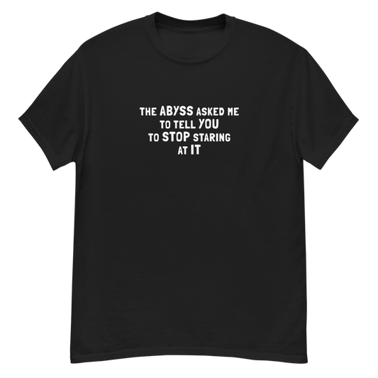 "The Abyss asked me to tell you to stop staring at it" printed on a black unisex classic tee laying on a flat surface