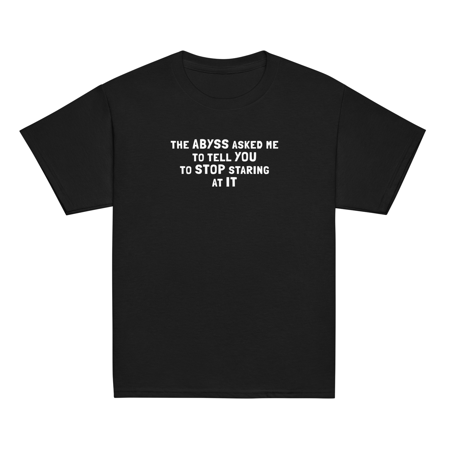"The Abyss asked me to tell you to stop staring at it" printed on a black youth classic tee laying on a flat surface