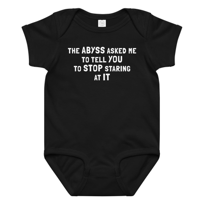 "The Abyss asked me to tell you to stop staring at it" printed on a black baby jersey bodysuit laying on a flat surface amongst other clothes