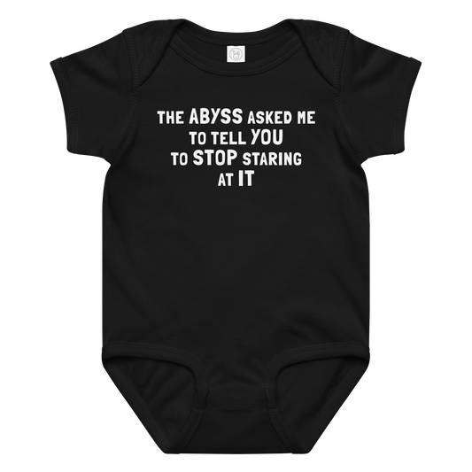 "The Abyss asked me to tell you to stop staring at it" printed on a black baby jersey bodysuit laying on a flat surface amongst other clothes