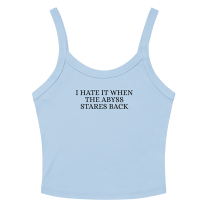 "I hate it when the abyss stares back" printed on a solid baby blue blend women's micro-rib tanktop laying on a flat surface amongst sunglasses and shorts