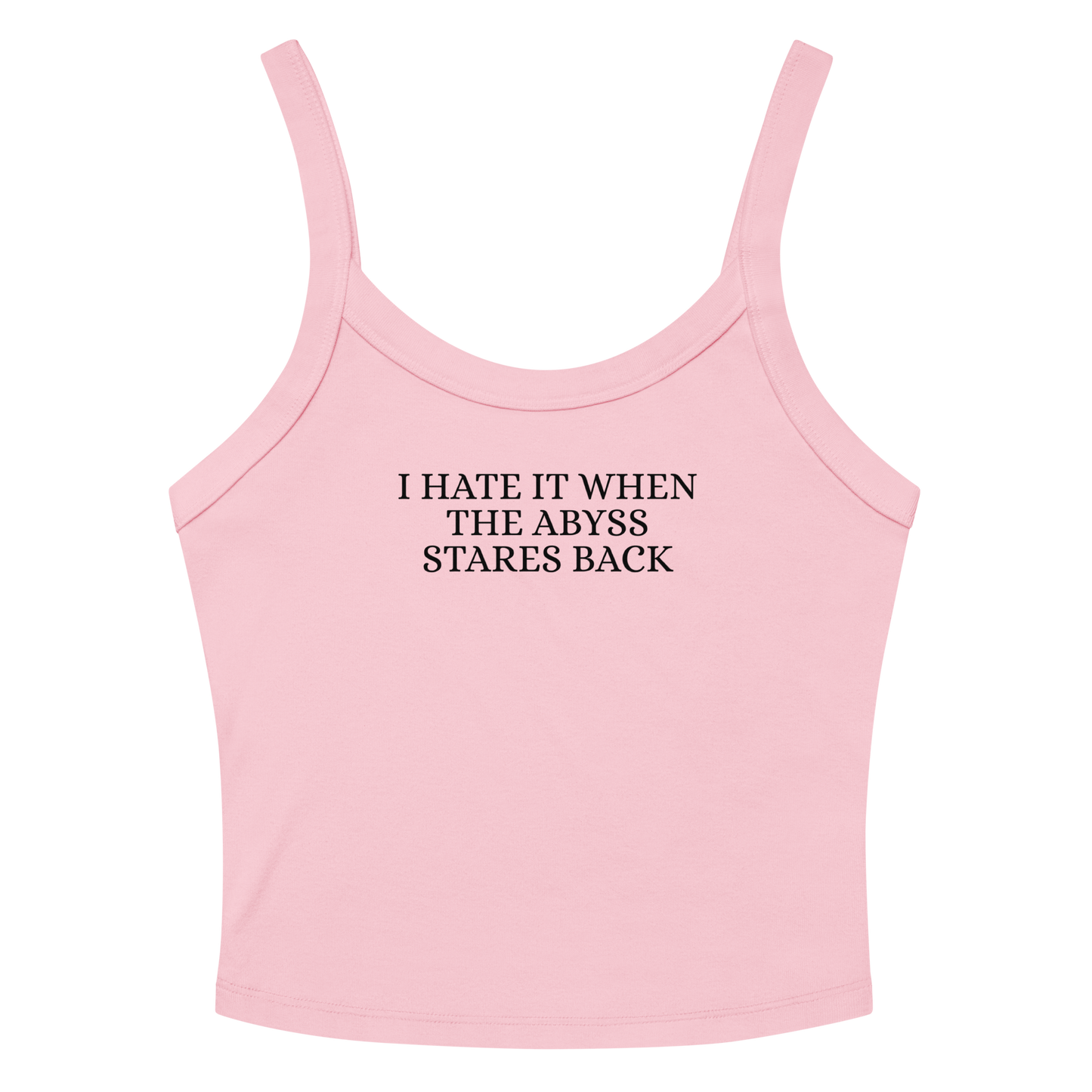 "I hate it when the abyss stares back" printed on a solid pink blend women's micro-rib tanktop laying on a flat surface amongst sunglasses and shorts