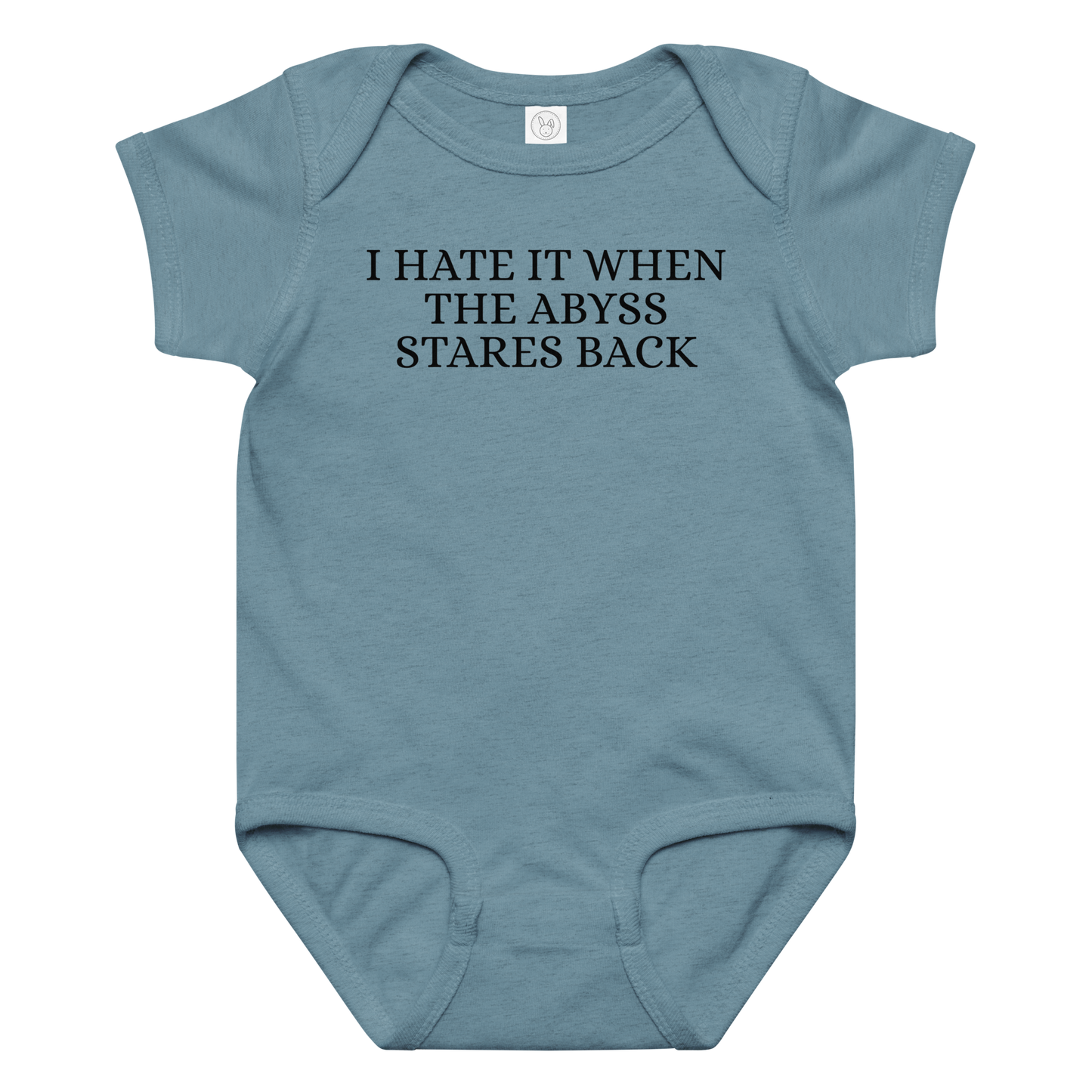 "I hate it when the abyss stares back" printed on a vintage indigo baby jersey bodysuit laying on a flat surface amongst other clothes
