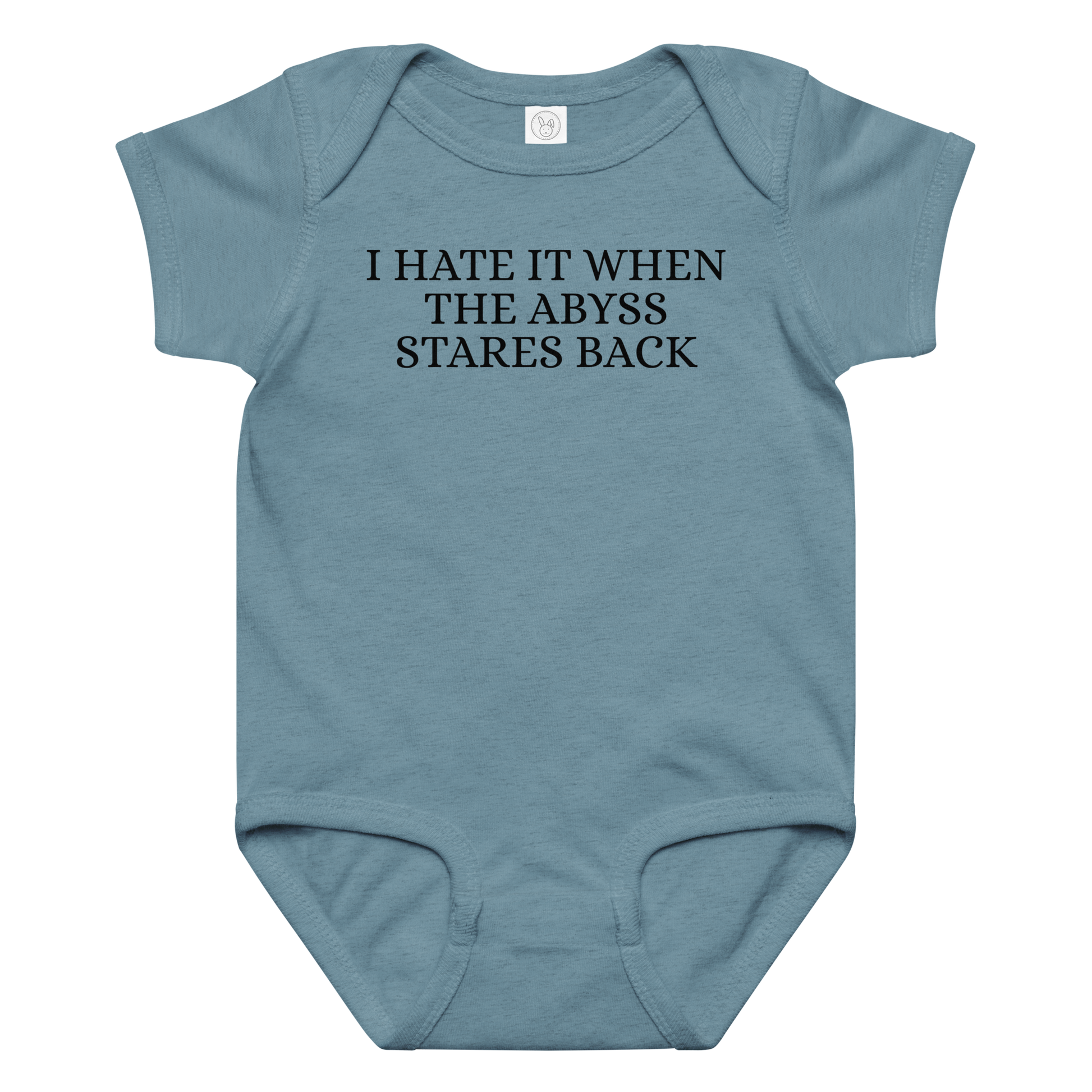 "I hate it when the abyss stares back" printed on a vintage indigo baby jersey bodysuit laying on a flat surface amongst other clothes