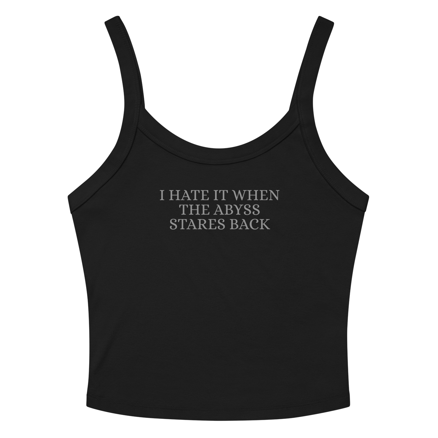 "I hate it when the abyss stares back" printed on a solid black blend women's micro-rib tanktop laying on a flat surface amongst sunglasses and shorts