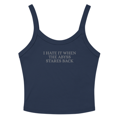 "I hate it when the abyss stares back" printed on a solid navy blend women's micro-rib tanktop laying on a flat surface amongst sunglasses and shorts