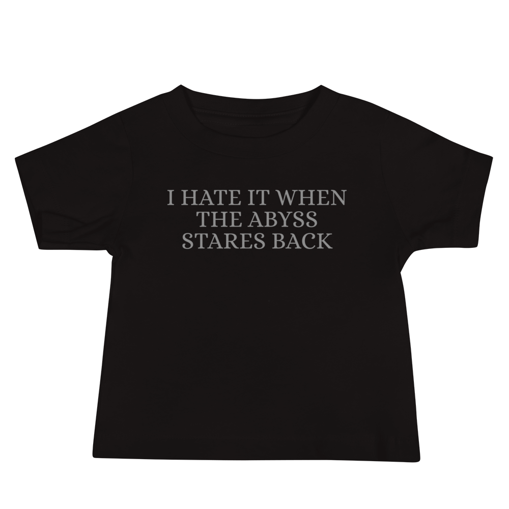 "I hate it when the abyss stares back" printed on a black baby jersey short sleeve tee laying on a flat surface