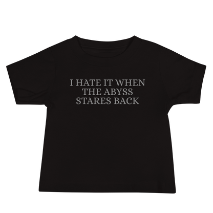 "I hate it when the abyss stares back" printed on a black baby jersey short sleeve tee laying on a flat surface