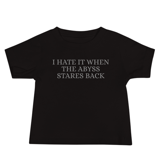 "I hate it when the abyss stares back" printed on a black baby jersey short sleeve tee laying on a flat surface
