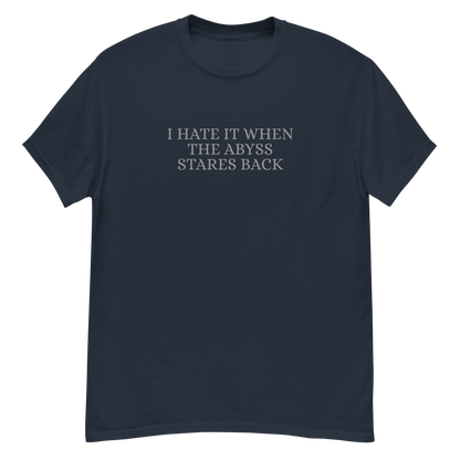 "I hate it when the abyss stares back" printed on a navy unisex classic tee laying on a flat surface