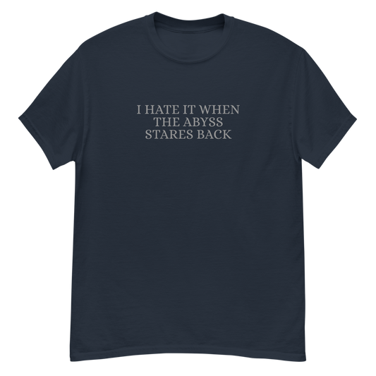 "I hate it when the abyss stares back" printed on a navy unisex classic tee laying on a flat surface