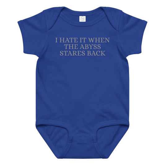 "I hate it when the abyss stares back" printed on a royal baby jersey bodysuit laying on a flat surface amongst other clothes