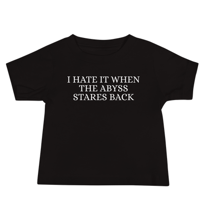 "I hate it when the abyss stares back" printed on a black baby jersey short sleeve tee laying on a flat surface