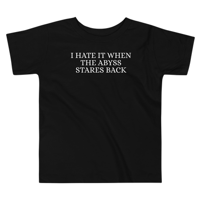 "I hate it when the abyss stares back" printed on a black toddler short sleeve tee laying on a flat surface