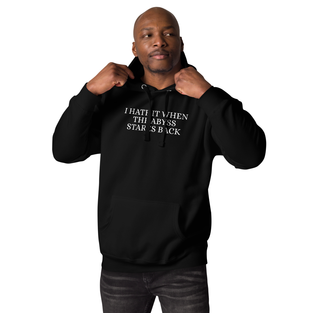 "I hate it when the abyss stares back" printed on a black unisex hoodie worn by a male
