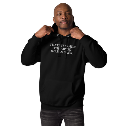 "I hate it when the abyss stares back" printed on a black unisex hoodie worn by a male