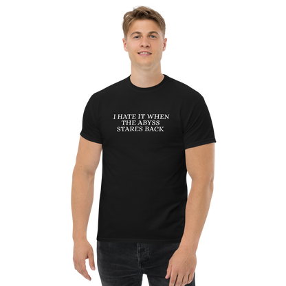 "I hate it when the abyss stares back" printed on a black unisex classic tee worn by a male